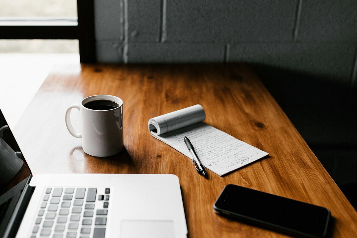 Bureau met laptop, notitieboek en koffie bij het kiezen van een verzekeringsadviseur