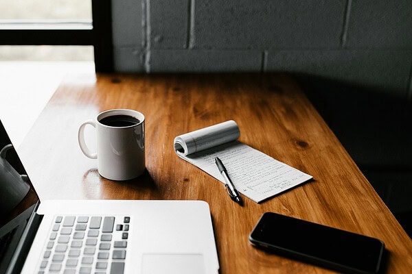 Bureau met laptop, notitieboek en koffie bij het kiezen van een verzekeringsadviseur