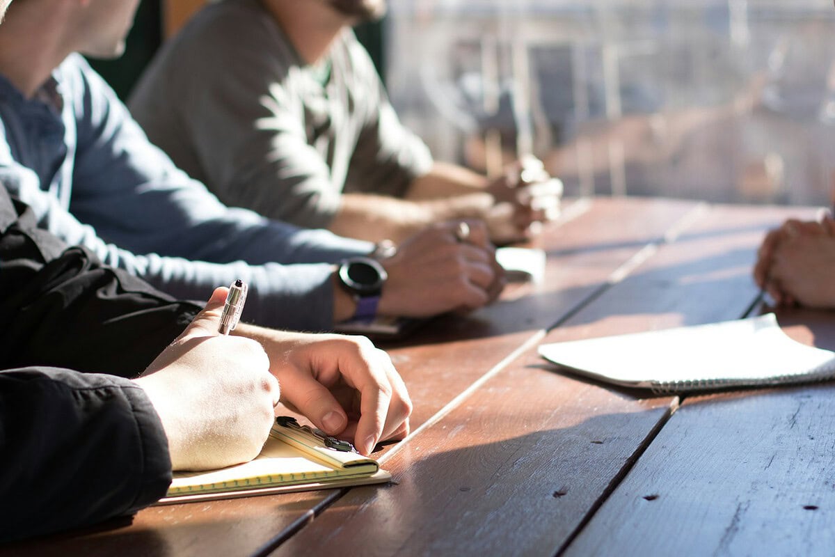 Ondernemers rond een tafel in overleg over een broodfonds of AOV
