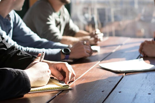 Ondernemers rond een tafel in overleg over een broodfonds of AOV